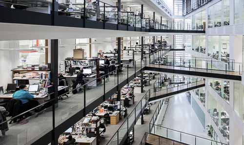 An atrium of a building with elevated walkways and workspaces down the sides.